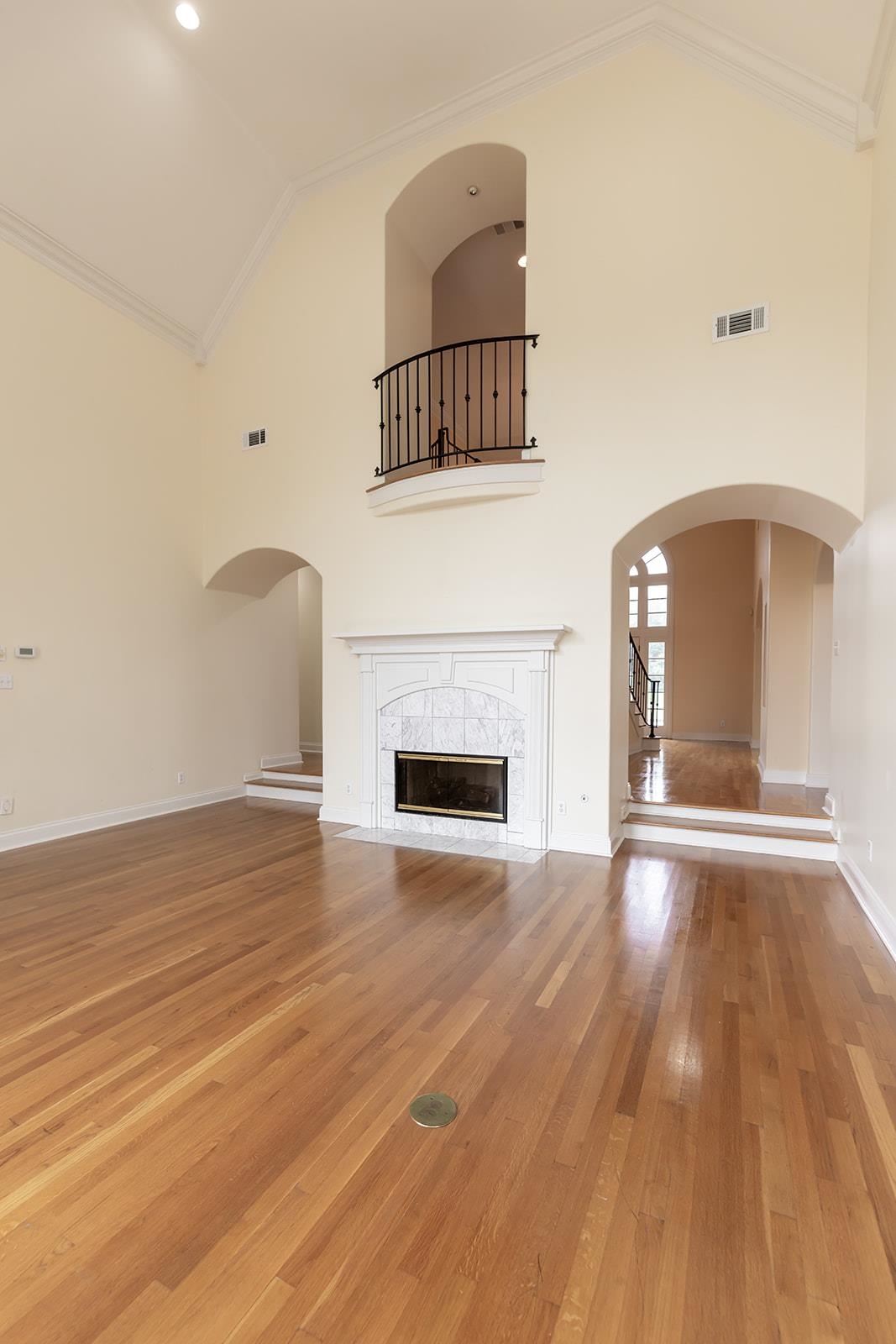 9390 Mayfield Road South Collierville, TN 38017 - Photo 21 of 40 Unfurnished living room featuring arched walkways, vaulted ceiling, ornamental molding, light wood-style floors, and a tile fireplace
