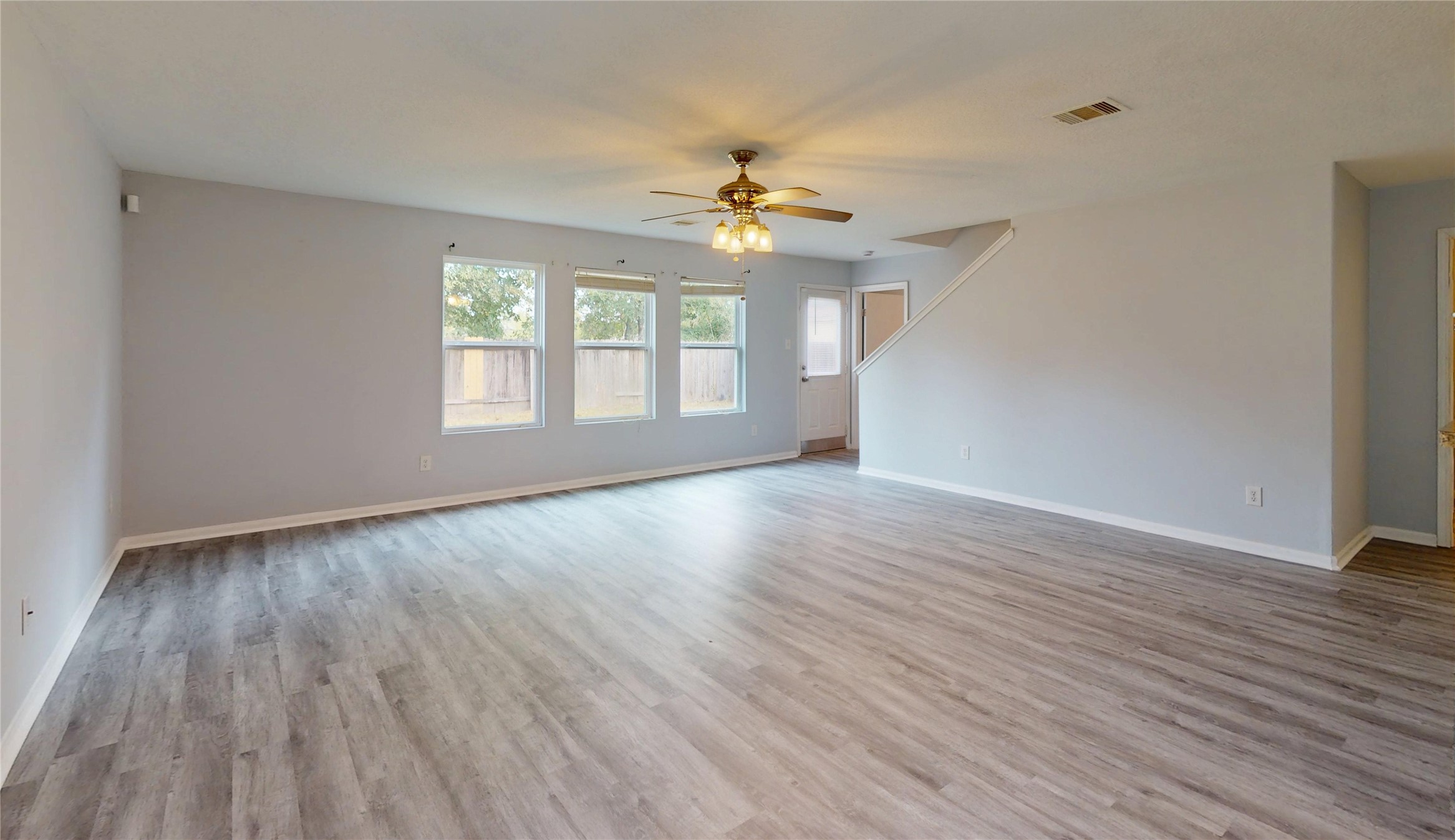 9877 Lace Flower Way Conroe, TX 77385 - Photo 4 of 43 an empty room with wooden floor chandelier fan and windows