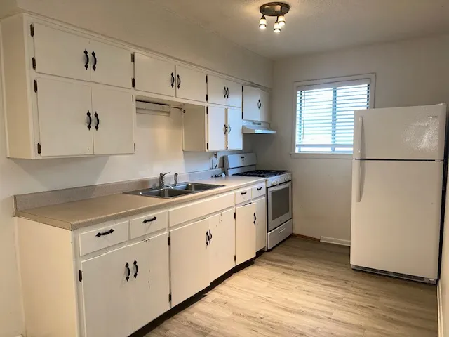 a kitchen with granite countertop white cabinets and white appliances