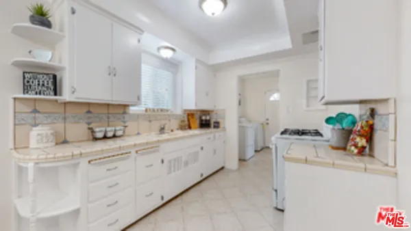 a kitchen with white cabinets and sink