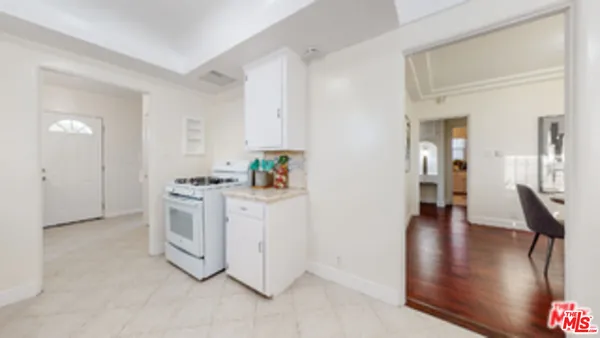 a kitchen with white cabinets and wooden floor