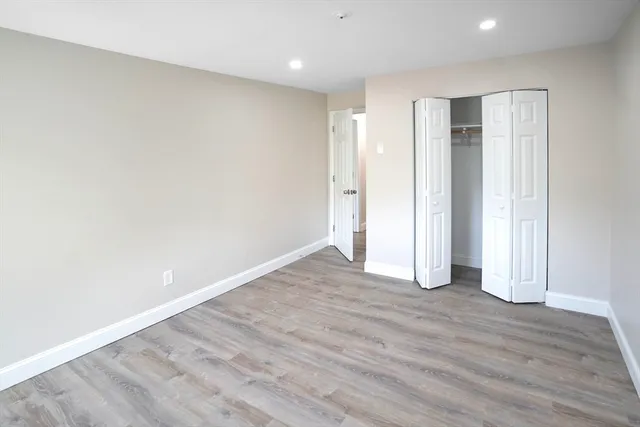 a view of an empty room with wooden floor and closet