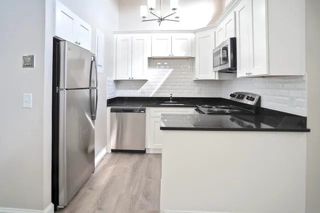 a kitchen with stainless steel appliances granite countertop a refrigerator a sink a stove a microwave and wooden floors