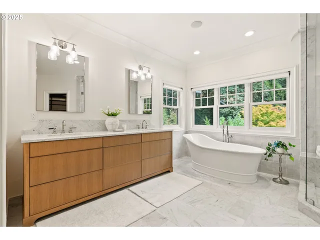 a spacious bathroom with a granite countertop double vanity sink a mirror and a bathtub