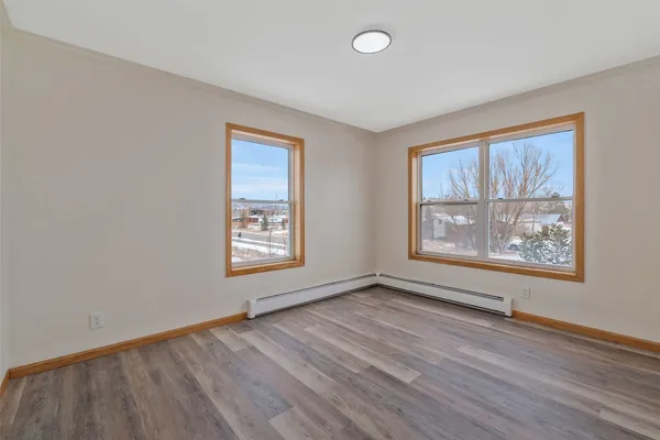 an empty room with wooden floor and windows