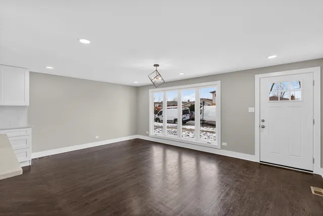 a view of a big room with wooden floor chandelier and windows