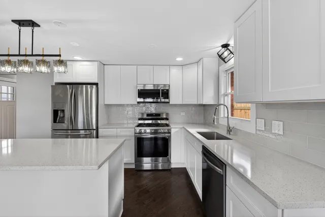 a kitchen with kitchen island granite countertop a sink stainless steel appliances and white cabinets