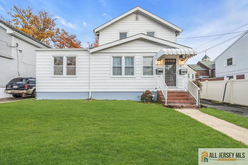 a view of a yard in front of a white house with plants and a large tree