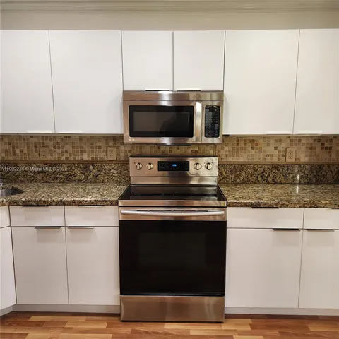 a kitchen with granite countertop a stove and a microwave