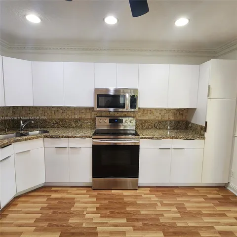 a kitchen with granite countertop stainless steel appliances and white cabinets
