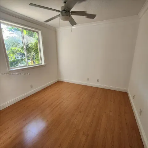 an empty room with wooden floor fan and windows