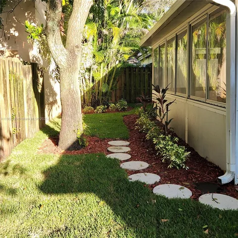 a view of backyard with potted plants and a large tree