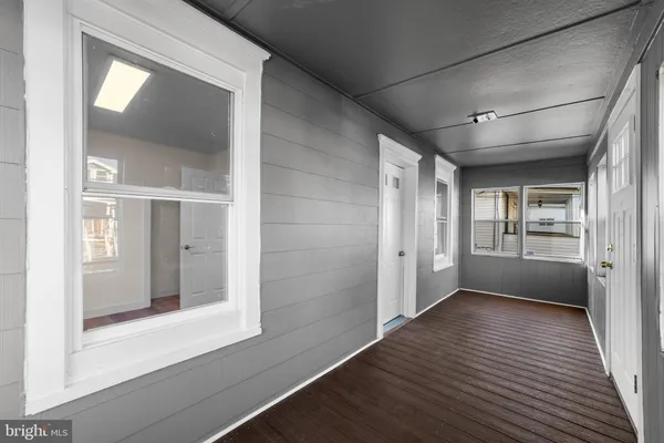 a view of a hallway with wooden floor and a living room