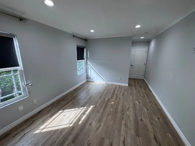 a view of empty room with wooden floor and fan