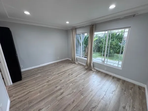 an empty room with wooden floor and windows