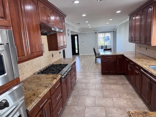 a large kitchen with stainless steel appliances granite countertop plenty wooden cabinets counter space a sink and a stove