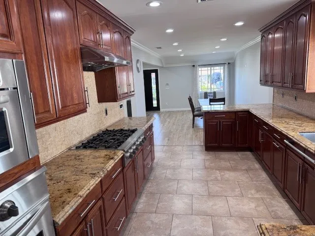 a large kitchen with stainless steel appliances granite countertop plenty wooden cabinets counter space a sink and a stove