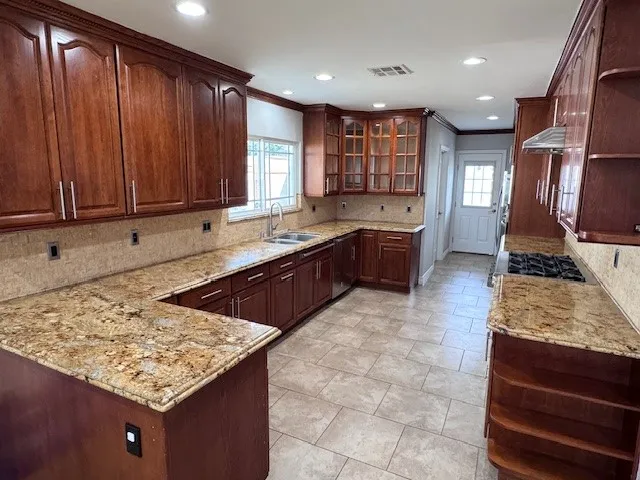 a kitchen with kitchen island granite countertop wooden cabinets a sink and dishwasher