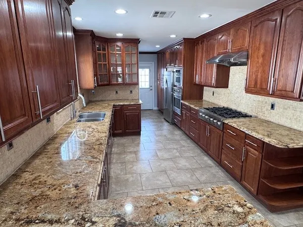 a large kitchen with kitchen island granite countertop wooden cabinets a granite counter tops and a stove