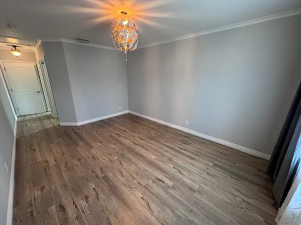 an empty room with wooden floor and chandelier fan