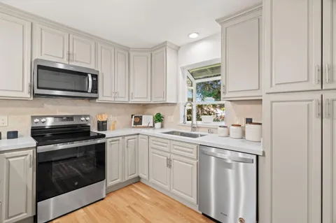 a kitchen with cabinets stainless steel appliances a sink and a window