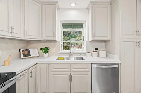a kitchen with stainless steel appliances granite countertop a sink a window and cabinets