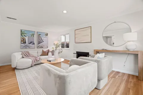 a living room with furniture a mirror and a wooden floor