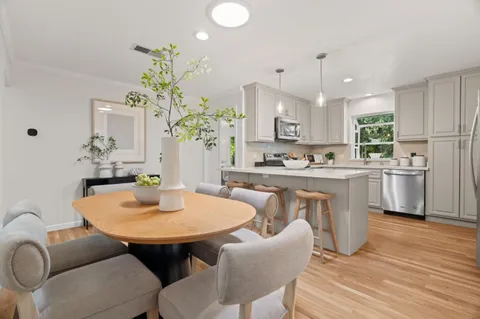 a open dining room with stainless steel appliances kitchen island granite countertop a dining table chairs and chandelier