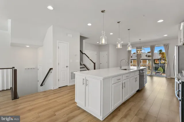a large kitchen with stainless steel appliances kitchen island a large counter top and wooden floors