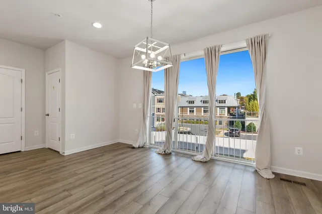 a view of an empty room with wooden floor and windows
