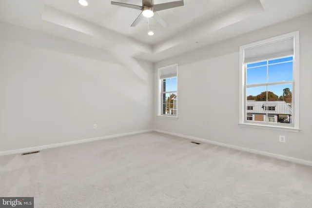 an empty room with windows and ceiling fan