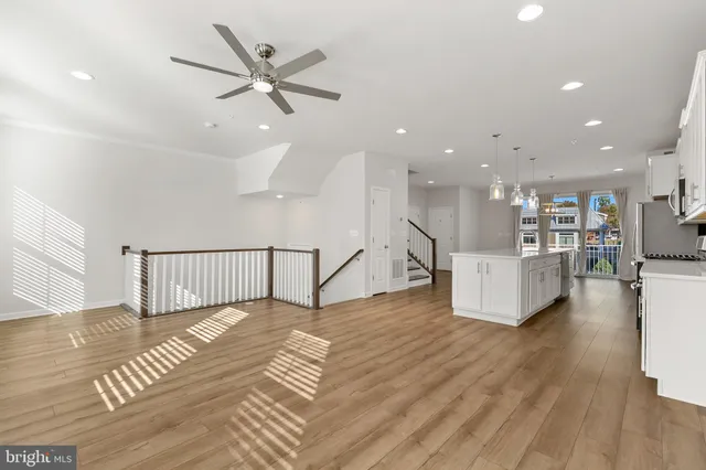 a view of an empty room with wooden floor and a ceiling fan