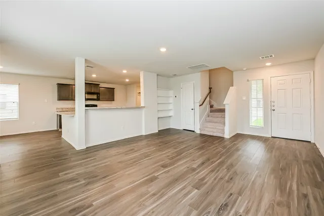 a view of a big room with wooden floors and kitchen view