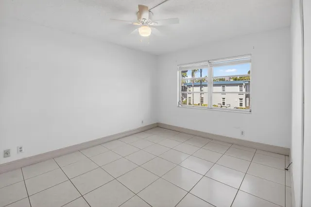 an empty room with windows and fan