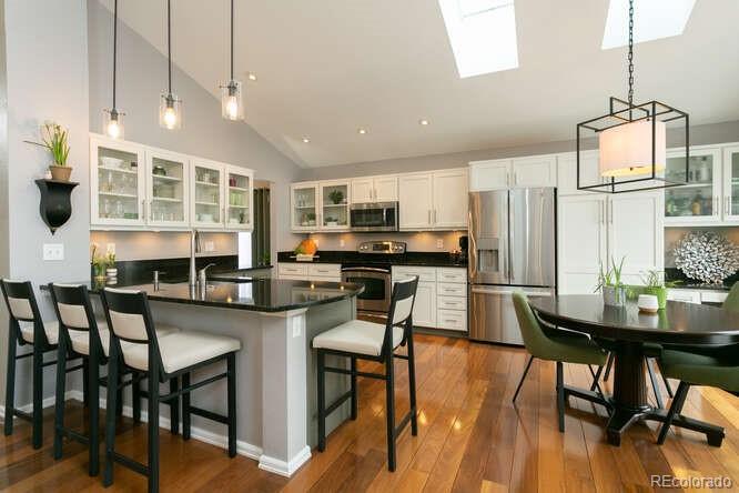 9772 Quay Loop Westminster, CO 80021 - Photo 5 of 36 a kitchen with stainless steel appliances granite countertop a stove top oven a dining table and chairs with wooden floor