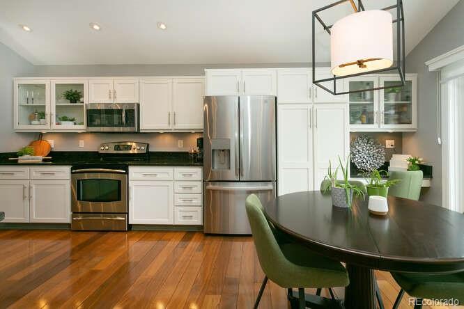 9772 Quay Loop Westminster, CO 80021 - Photo 7 of 36 a kitchen with a table chairs stainless steel appliances and cabinets