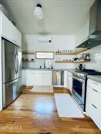 a large kitchen with stainless steel appliances granite countertop a stove top oven a refrigerator and white cabinets