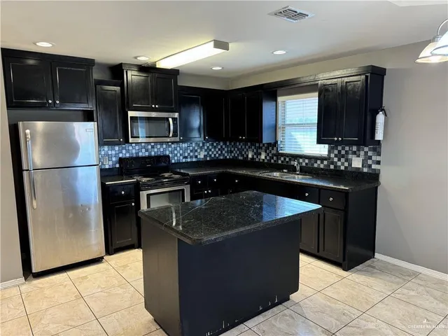 a kitchen with stainless steel appliances granite countertop a sink a refrigerator and a stove