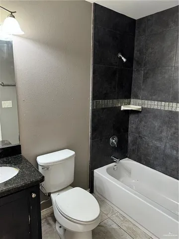 a bathroom with a granite countertop toilet and a bathtub