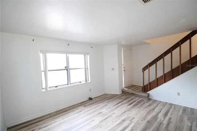 a view of an empty room with wooden floor and windows