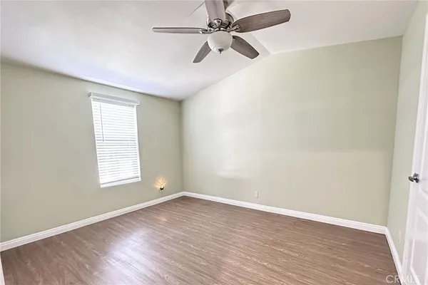 an empty room with wooden floor fan and windows