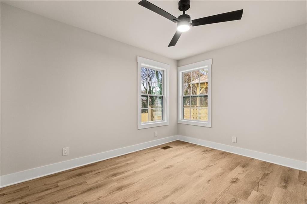 4203 Annistown Road Snellville, GA 30039 - Photo 21 of 32 an empty room with wooden floor ceiling fan and windows