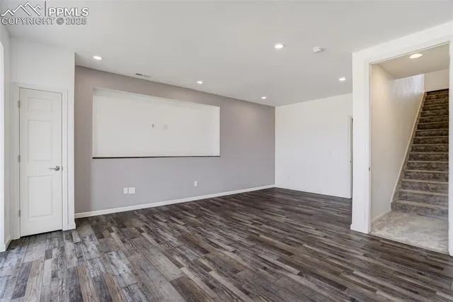 a view of an empty room with wooden floor and entryway