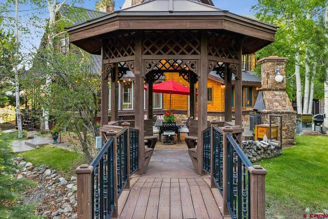 a view of a big house with a big yard and potted plants and large trees