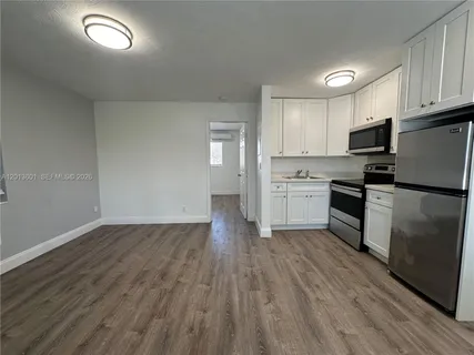 a kitchen with granite countertop a refrigerator oven a sink dishwasher and wooden floor