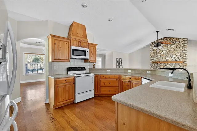 a kitchen with stainless steel appliances granite countertop a sink dishwasher stove and microwave with wooden floor
