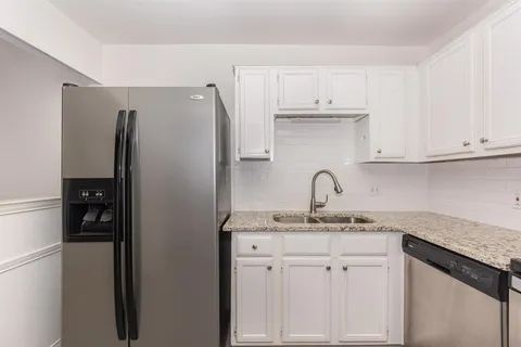 a kitchen with white cabinets and refrigerator