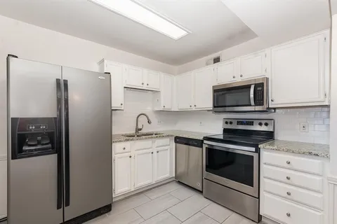 a kitchen with white cabinets stainless steel appliances and sink