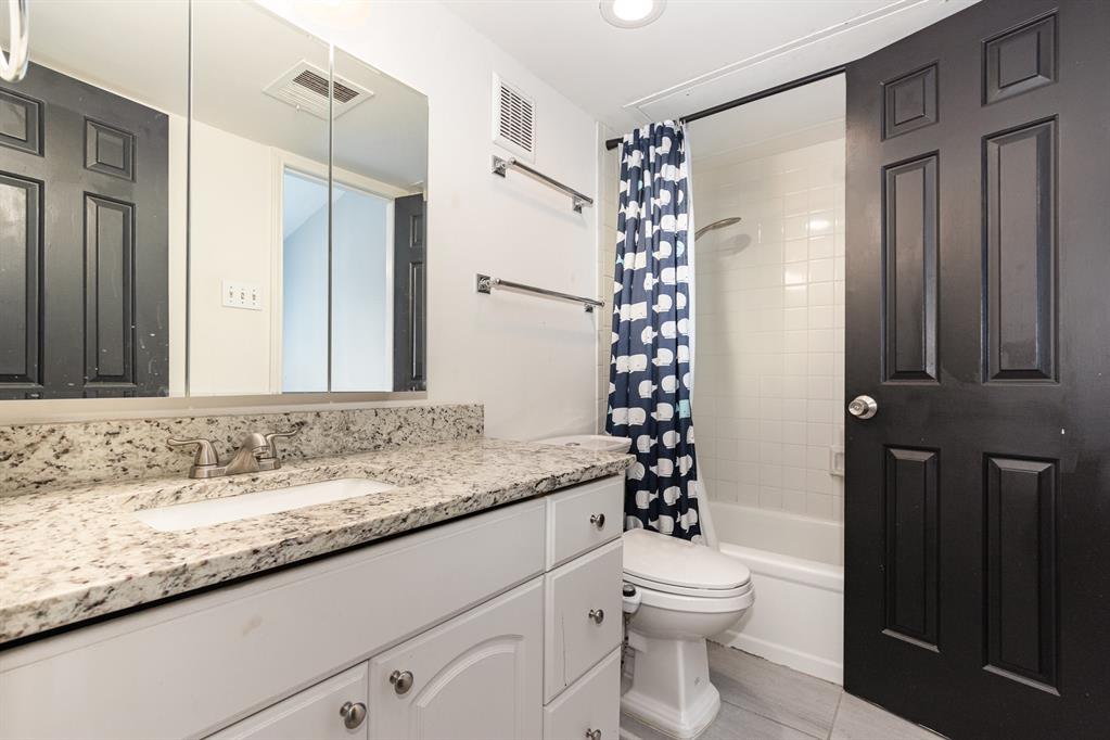 8750 Park Lane, Unit 151 Dallas, TX 75231 - Photo 21 of 33 a bathroom with a granite countertop sink a toilet and shower