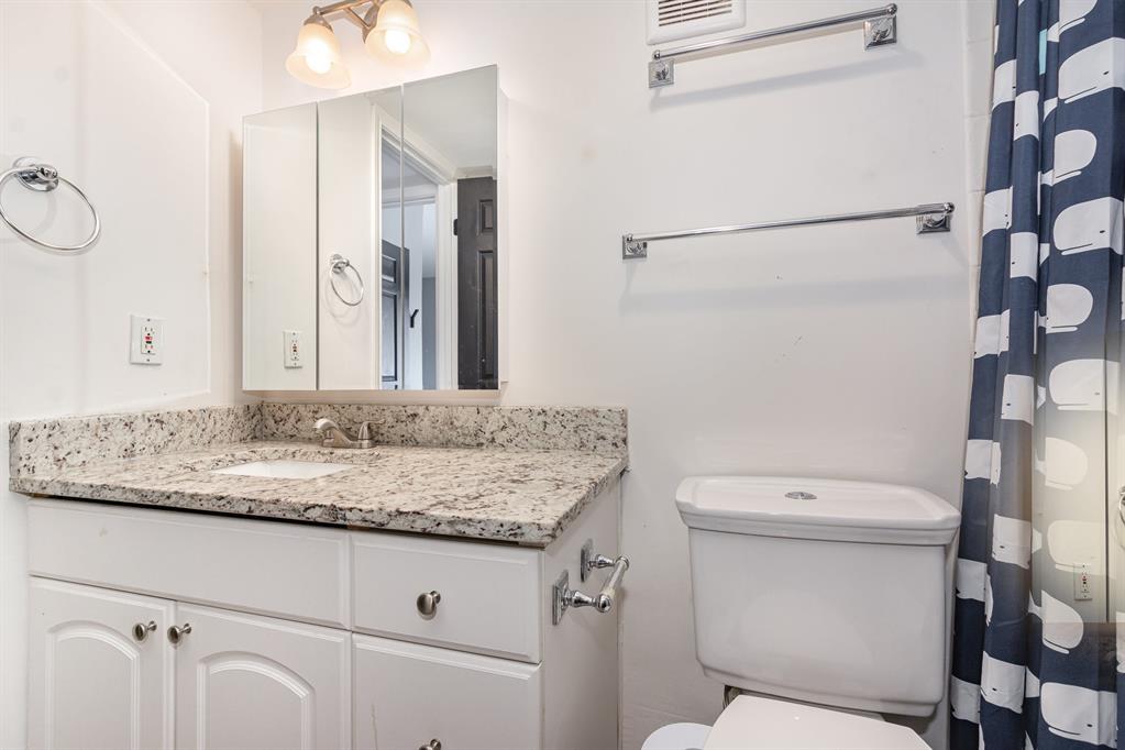 8750 Park Lane, Unit 151 Dallas, TX 75231 - Photo 27 of 33 a bathroom with a granite countertop sink toilet and shower